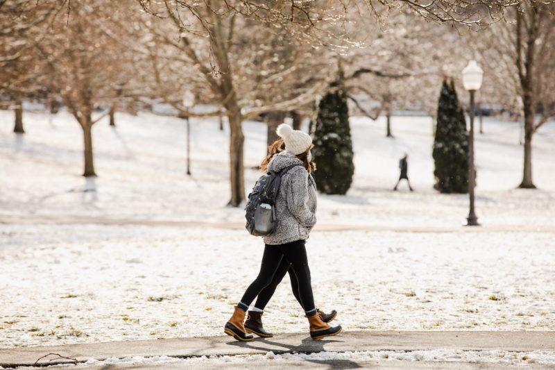 Students walk across Virginia Tech campus in winter, with snow on the ground.