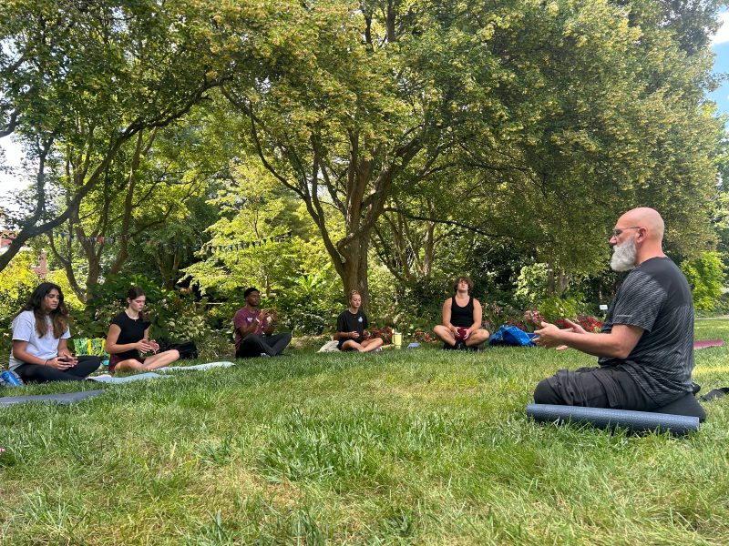 Students sitting in a circle outside, meditating.